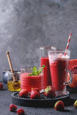 Üç farklı kırmızı meyve karpuz, çilek, ahududu, nar kokteyl veya ezilmiş buz, nane ve siyah doku tablo yukarıda malzemeler ile bardaklarda smoothies berry. Gıda natürmort.