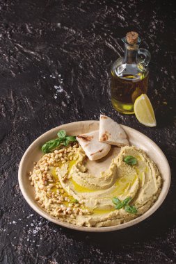 Ev yapımı geleneksel yayılmış humus çam fıstığı, zeytin yağı, fesleğen ile karanlık doku arka plan üzerinde pide ekmek ve zeytinyağı opl ile seramik plaka üzerinde görev yaptı. Akdeniz snack.
