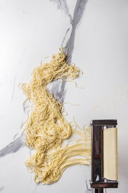 Ev yapımı İtalyan pişmemiş makarna spagetti makarna makine üreticisi ile İrmik unu beyaz mermer doku arka plan üzerinde rulo hamur. Düz lay, uzay.
