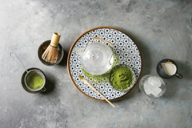 İçki matcha buz yapmak için malzemeler. Yeşil çay matcha tozu seramik kase, geleneksel bambu kaşık, plaka, cam Çaydanlık, çırpma teli buz küpleri gri doku arka plan üzerinde. Düz lay, uzay