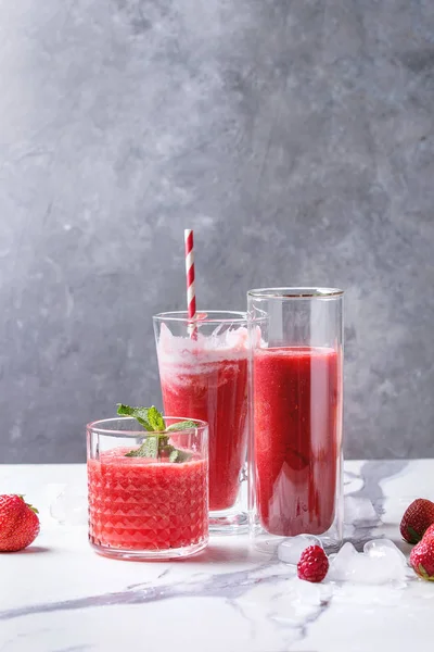 Üç farklı kırmızı meyve karpuz, çilek, ahududu, nar kokteyl veya ezilmiş buz, taze nane ve beyaz mermer tablo yukarıda malzemeler bardaklarda smoothies berry.