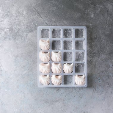 Gri doku arka plan üzerinde karides plastik kutu tarafından doldurulmuş Asya potstickers köfte yemek için hazır dondurulmuş. Düz lay, alan. Stoklar ürün. Kare görüntü