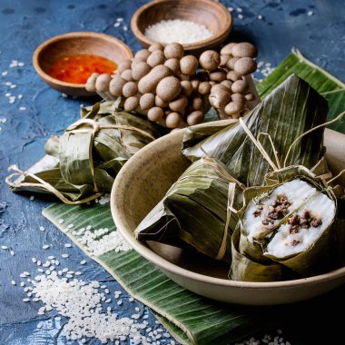 Seramik kase hizmet muz yaprakları doldurma etli köfte pirinç tapyoka un dan Asya pirinç piramidal biraz uzun tuttum. Mavi doku arka plan üzerinde malzemeler yukarıda. Yakın çekim. Kare görüntü