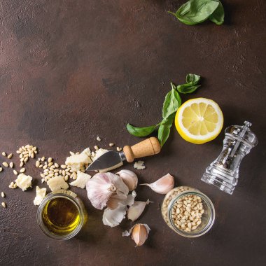 Geleneksel fesleğen pesto sos taze fesleğen, zeytinyağı, parmesan peyniri, sarımsak, çam fıstığı, limon karanlık doku arka plan üzerinde yukarıdaki malzemelerle cam kavanoza. Üstten görünüm alanı. Kare görüntü