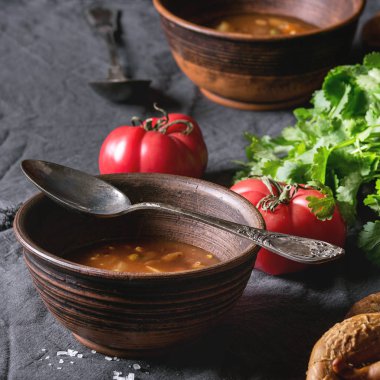 Vejetaryen sıcak havuç domates bezelye patates çorbası, eski ahşap tahta masa üzerinde taze kişniş, Simit Ekmek ve tekstil peçete üzerinde domates ile servis ile kil kase. Rustik tarzı yemek. Kare görüntü