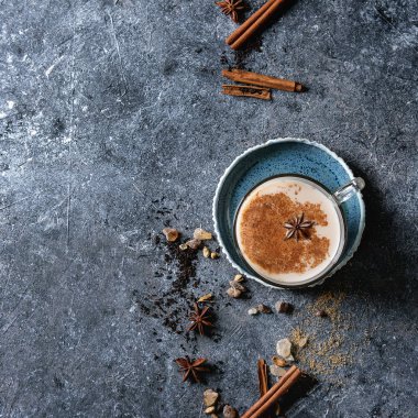 Cam fincan geleneksel Hint masala chai çay yukarıdaki malzemelerle mavi daire. Tarçın, kakule, anason, şeker, karanlık doku arka plan üzerinde siyah çay. Görünümü en çok, uzay kopyalayın. Kare görüntü