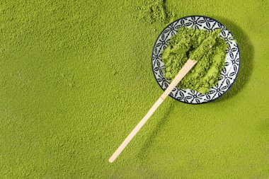 Green tea matcha powder in ceramic bowl with traditional bamboo spoon over powdering matcha as background. Flat lay, copy space clipart