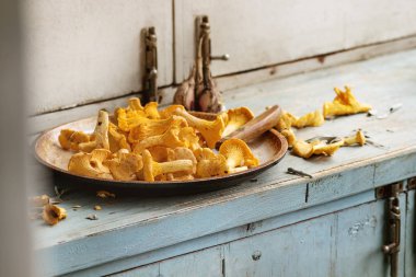 Tavada mavi beyaz ahşap mutfak masasında çiğ çiğ Chanterelles orman mantar. Rustik tarzı, gün ışığı, kopya alanı