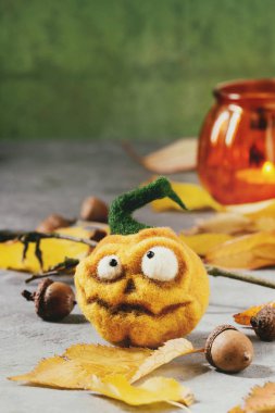 Komik zanaat Cadılar Bayramı veya kabak jack o fener tatil dekor sarı sonbahar yaprakları ve meşe palamutları ile gri doku arka plan üzerinde iğne..