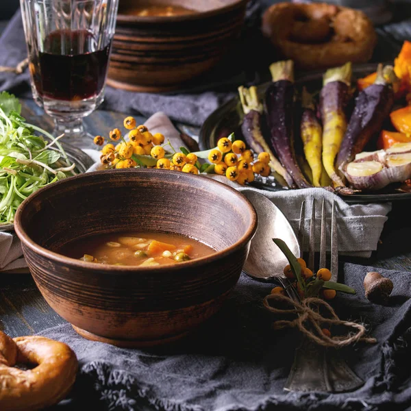 Pişirme kabak, havuç, sarımsak, taze kişniş, Simit Ekmek, kırmızı şarap, tatil dekorasyon sofra sıcak çorba, Kazanlı ahşap masa üzerinde meyveleri. Rustik tarzı. Kare görüntü