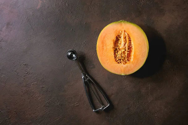 半成熟的有机甜瓜与种子和勺子在深褐色纹理背景 — 图库照片