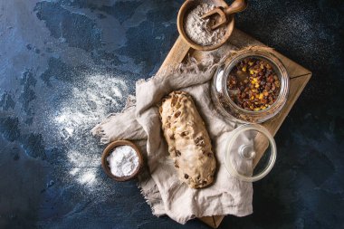 Christmas cake, geleneksel Alman şenlikli pişirme. Kepekli hamur stollen hazırlık ile keten peçete üzerine un ve kuru üzüm koyu mavi doku arka plan üzerinde kase. Üstten görünüm, uzay