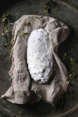 Tüm Christmas cake, geleneksel Alman şenlikli pişirme. Kepekli stollen kuru üzüm ve ökseotu eski karanlık metal arka plan üzerinde dalları ile keten peçete üzerine pudra şekeri ile. Üstten görünüm, uzay