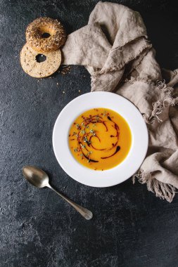 Vejetaryen vegan Kabak havuç çorbası balsamik sirke tarafından dekore edilmiş ve kekik otlar, kaşık, Simit Ekmek, biber ve bez ile siyah doku arka plan üzerinde servis tabak. Düz lay, uzay