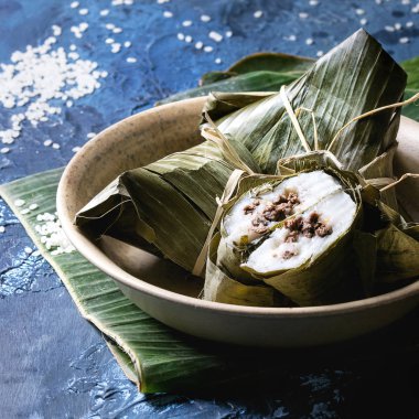 Mavi doku arka plan üzerinde seramik bowlwith pirinç sunulan muz yaprakları doldurma etli köfte pirinç tapyoka un dan Asya pirinç piramidal biraz uzun tuttum. Yakın çekim, uzay. Kare görüntü