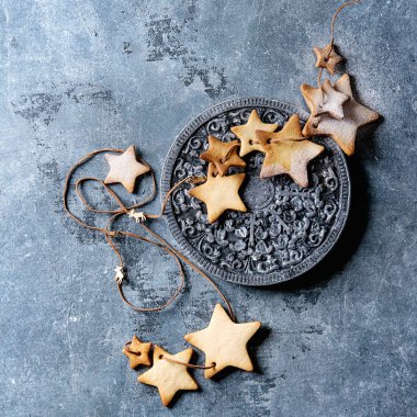 Ev yapımı kurabiye yıldız şekli şeker kurabiye farklı boyutu ile süslü ahşap iş parçacığında pudra şekeri ile mavi doku yüzeyi üzerine kurulu. Noel tedavi arka plan. Üstten görünüm alanı. Kare görüntü