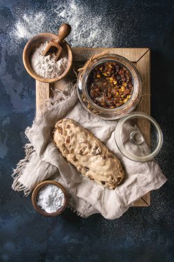 Christmas cake, geleneksel Alman şenlikli pişirme. Kepekli hamur stollen hazırlık ile keten peçete üzerine un ve kuru üzüm koyu mavi doku arka plan üzerinde kase. Üstten görünüm, uzay