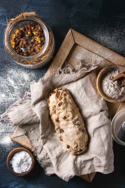 Christmas cake, geleneksel Alman şenlikli pişirme. Kepekli hamur stollen hazırlık ile keten peçete üzerine un ve kuru üzüm koyu mavi doku arka plan üzerinde kase. Üstten görünüm, uzay