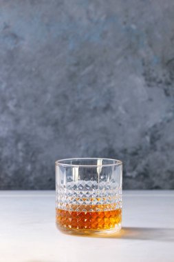 Bir bardak scotch viski ayakta arka plan, gri duvar beyaz mermer masada. Alkol içki.
