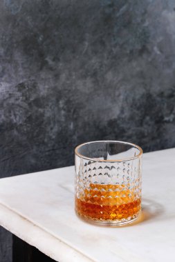 Bir bardak scotch viski ayakta arka plan, gri duvar beyaz mermer masada. Alkol içki.