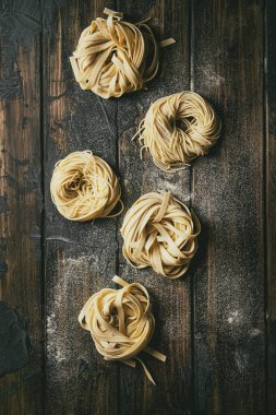 Çeşitli İtalyan ev yapımı ham pişmemiş makarna makarna ve İrmik unu kara tahta doku ahşap masa üzerinde ile tagliatelle. Düz lay, uzay