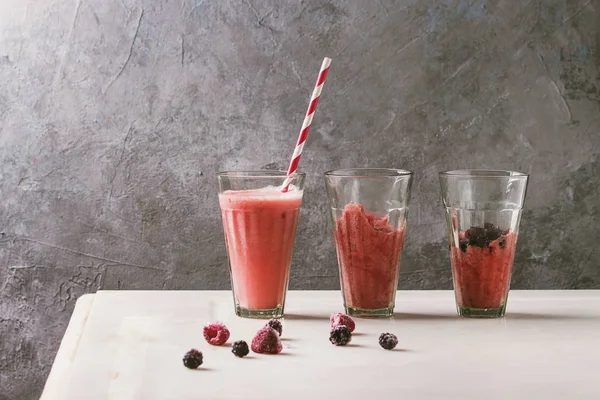 赤い果実のベリー スイカ アイス カクテルと冷凍ジュース シャーベット グラス ストライプ ストローで背景に灰色の壁と白大理石のテーブルの上に立ちます 夏の冷たい飲み物 — ストック写真
