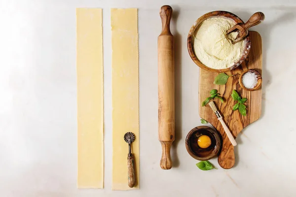 自家製イタリアン パスタ ラビオリほうれん草リコッタ セモリナ粉 卵の黄身 バジル オリーブの木製調理器具ボウル スクープ 麺棒でスタッフの材料 白い大理石の背景 — ストック写真