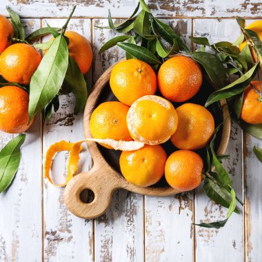 Olgun organik clementines veya mandalina ile ahşap tahta üzerinde beyaz ahşap tahta masa arka plan olarak hizmet veren yapraklarda. Üstten görünüm alanı. Sağlıklı beslenme. Kare görüntüleri