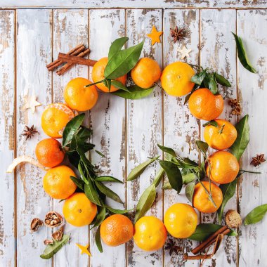 Clementines mandalina yapraklar gibi Noel çelenk tarçın ve anason üzerinde beyaz ahşap tahta arka plan ile. Üstten görünüm alanı. Yeni yıl kartları ve süslemeleri. Kare görüntüleri