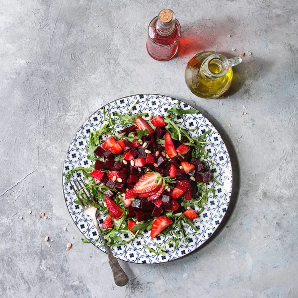 甜菜根和草莓沙拉在陶瓷板上配有芝麻和坚果 上面有水果 Ocet 和橄榄油 上面有灰色纹理背景 顶部视图 复制空间 健康饮食 — 图库照片
