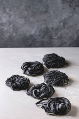 İtalyan ev yapımı çiğ çiğ mürekkep balığı çeşitli mürekkep siyah Makarna Makarna ve İrmik unu beyaz mermer tablo ile tagliatelle. Kopya alanı.