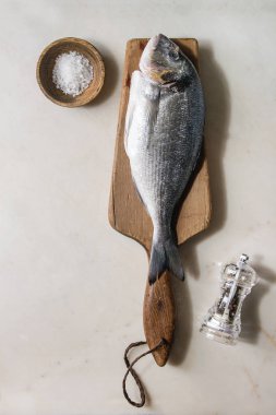 Çiğ çiğ yıkılmış çipura veya ahşap kesme tahtası buz, tuz ve biber üzerine beyaz mermer zemin ile dorado balık. Yat, alanı Kopyala. Pişirme kavramı