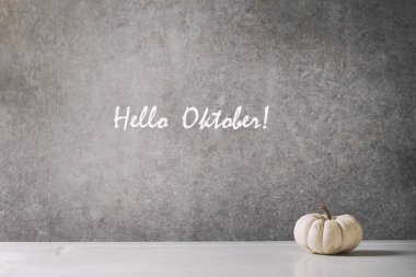 Arka plan gri duvara beyaz mermer masada beyaz bütün pişmemiş dekoratif balkabağı. Sonbahar minimalist dekorasyon. Yazıt Merhaba Oktober.