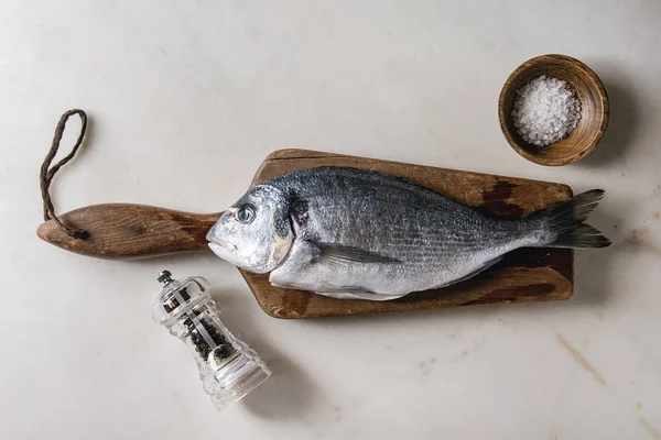 Çiğ çiğ yıkılmış çipura veya ahşap kesme tahtası buz, tuz ve biber üzerine beyaz mermer zemin ile dorado balık. Yat, alanı Kopyala. Pişirme kavramı