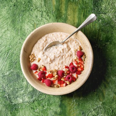 Tatlı pirinç lapası pudingi çilek çilek ve ahududu, ceviz yeşil doku arka plan üzerinde seramik plaka. Üstten görünüm alanı. Kare görüntü