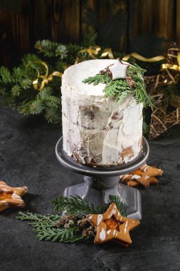 Noel ev yapımı beyaz çıplak kek yıldız çerezi tarafından dekore edilmiş ve pasta dallarda yeşil mazı çam ağacı, kurabiye ve yukarıda xmas dekorasyon siyah masada stand. Karanlık rustik tarzı.