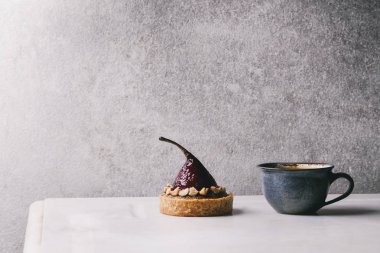 Arka plan, gri Duvar ile beyaz mermer masa üzerinde duran kahve espresso fincan ile tatlı kırmızı şarap tartı. Minimalist tarzı. Kopya alanı