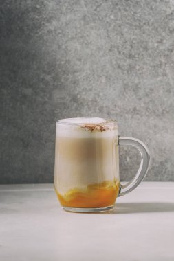 Cam kabak spice latte kabak püresi, süt köpüğü ve arka plan, gri duvar beyaz mermer masada tarçın ayakta katmanlı. Kopya alanı