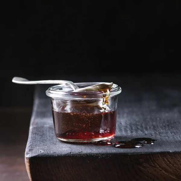 自制液体透明红糖焦糖在玻璃瓶与勺子站在黑色木板上 正方形图像 — 图库照片