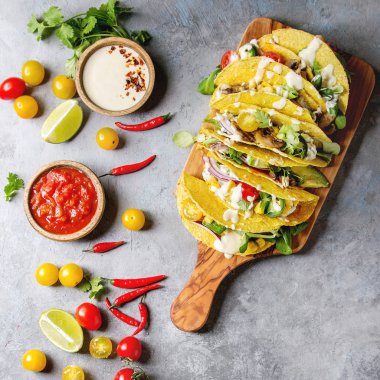 Çeşitli vejetaryen Mısır Tacos sebze, yeşil salata ile servis krem soslar ve malzemeler yukarıda ile zeytin ahşap tahta üzerinde gri doku arka plan üzerinde. Üstten görünüm alanı. Kare görüntü
