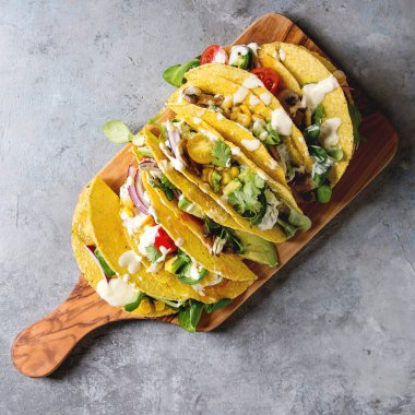 Çeşitli vejetaryen Mısır Tacos sebze, yeşil salata, biber ile krema sosu ile zeytin ahşap tahta üzerinde gri doku arka plan üzerinde servis. Görünümü en çok, uzay kopyalayın. Kare görüntü