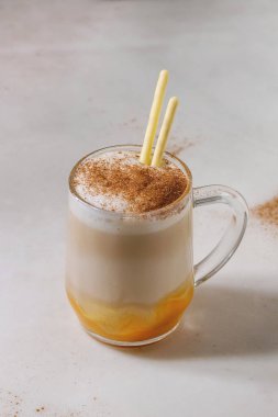 Bardak kabak katmanlı spice latte kabak püresi, süt köpüğü, tatlı ile sopa ve beyaz mermer masa üzerinde tarçın duran sırlı. Kopya alanı