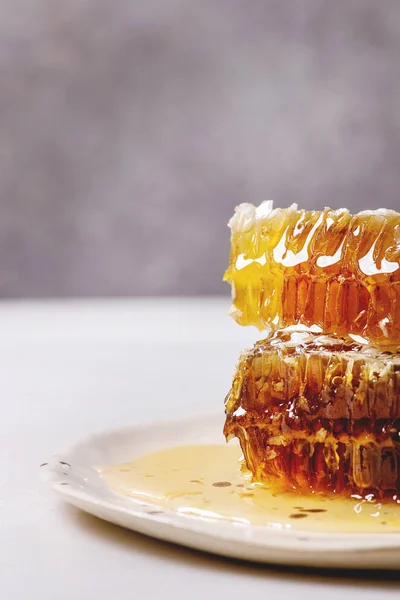 白い大理石のテーブルに斑点を付けられたセラミック プレートにハニカム構造の有機蜂蜜のスタック — ストック写真