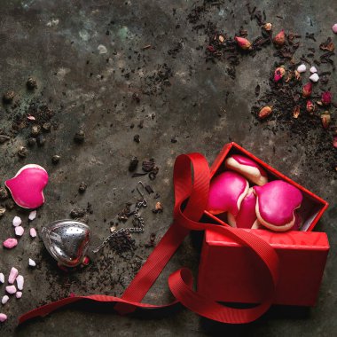 Sevgililer günü tebrik kartı çeşitli kuru çay, gül tomurcukları, kalp şekli ev yapımı badem kurabiye hediye, şeker pembe ve kırmızı kurdele ile eski karanlık metal arka plan üzerinde seviyorum. Üstten görünüm. Kare görüntü