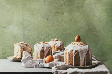 Ayarla geleneksel Rus ve Ukraynalı Paskalya kek Kulich Paska ekmek badem ile tüm sırlı ve dilimlenmiş, hizmet üzerinde seramik plaka ile yeşil duvar arka plan olarak tabloda bezle. Tonlu görüntü
