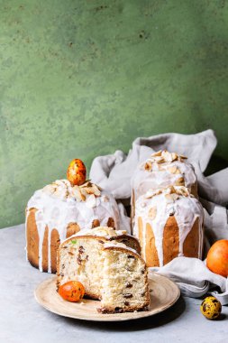 Ayarla geleneksel Rus ve Ukraynalı Paskalya kek Kulich Paska ekmek badem ile tüm sırlı ve dilimlenmiş, hizmet üzerinde seramik üzerinde gri arka plan olarak yeşil duvar tabloyla bezle plakası.