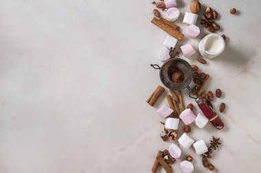Sıcak çikolata için malzemeler. Deli pembe büyük hatmi, kakao çekirdekleri, kakao tozu, tarçın, krem, kıyılmış çikolata, beyaz mermer arka plan üzerinde beyaz. Düz lay, alan. Tatlı yiyecek ve içecek.