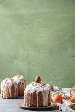 Ayarla geleneksel Rus ve Ukraynalı Paskalya kek Kulich Paska ekmek badem ile tüm sırlı ve dilimlenmiş, hizmet üzerinde seramik üzerinde gri arka plan olarak yeşil duvar tabloyla bezle plakası.