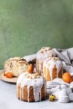 Ayarla geleneksel Rus ve Ukraynalı Paskalya kek Kulich Paska ekmek badem ile tüm sırlı ve dilimlenmiş, hizmet üzerinde seramik üzerinde gri arka plan olarak yeşil duvar tabloyla bezle plakası.