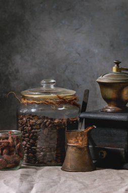 Kahve koleksiyonu. Kavanoz, vintage kahve değirmeni, jezve pot kavrulmuş siyah kahve çekirdekleri, tatlı badem ayakta keten masa örtüsü ile tabloda sekerli..